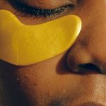 Salons - Crop gentle African American female with closed eyes and clean face enjoying cosmetic procedure for smoothing and moisturizing skin under eyes and removing dark circles