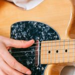 Hobbies - Woman in White Crew Neck T shirt Playing Brown and Black Electric Guitar