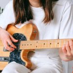 Hobbies - Woman In White Shirt Playing Brown Electric Guitar