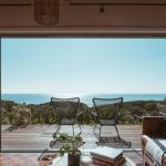 Accommodations - Interior design of luxurious apartment with large balcony doors and wooden terrace having picturesque view on green forested seashore and calm blue sea