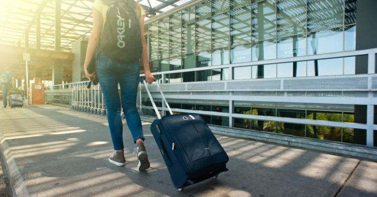 Travel - Woman Walking on Pathway While Strolling Luggage