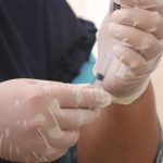 Injury Prevention - Person in Black Scrubs and White Latex Gloves Holding Syringe