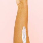 Therapy - Female arm with smear for skin care against pink background