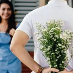 Dating - Man Holding Baby's-breath Flower in Front of Woman Standing Near Marble Wall