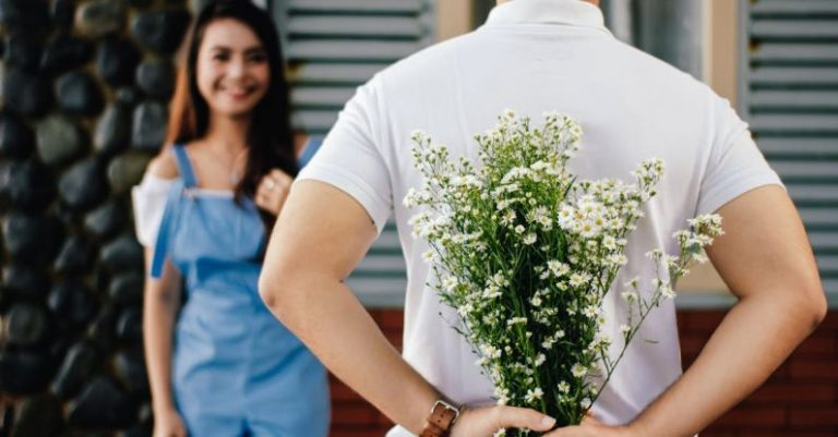 Dating - Man Holding Baby's-breath Flower in Front of Woman Standing Near Marble Wall
